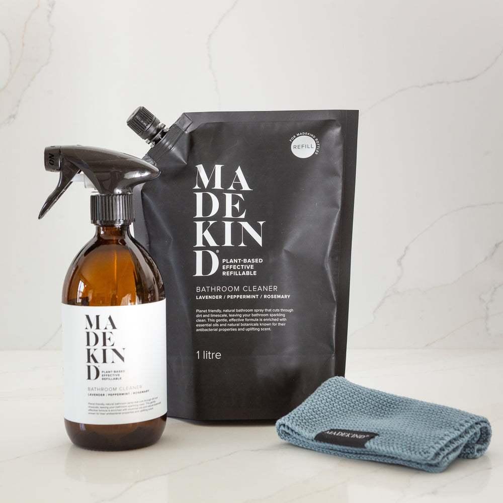 Madekind cleaning products including a spray bottle, refill pouch, and blue dishcloth on a light background