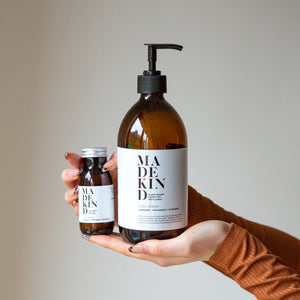 Photo of hands holding a 500ml bottle of MadeKind natural dish wash and a mini bottle of MadeKind natural dish wash