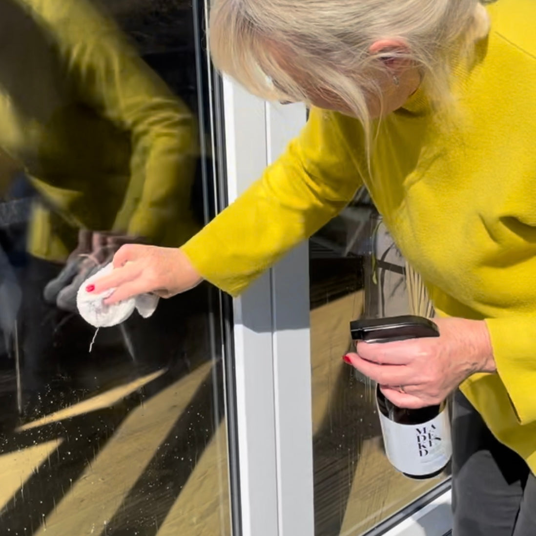 Woman cleaning windows with eco friendly multi surface spray