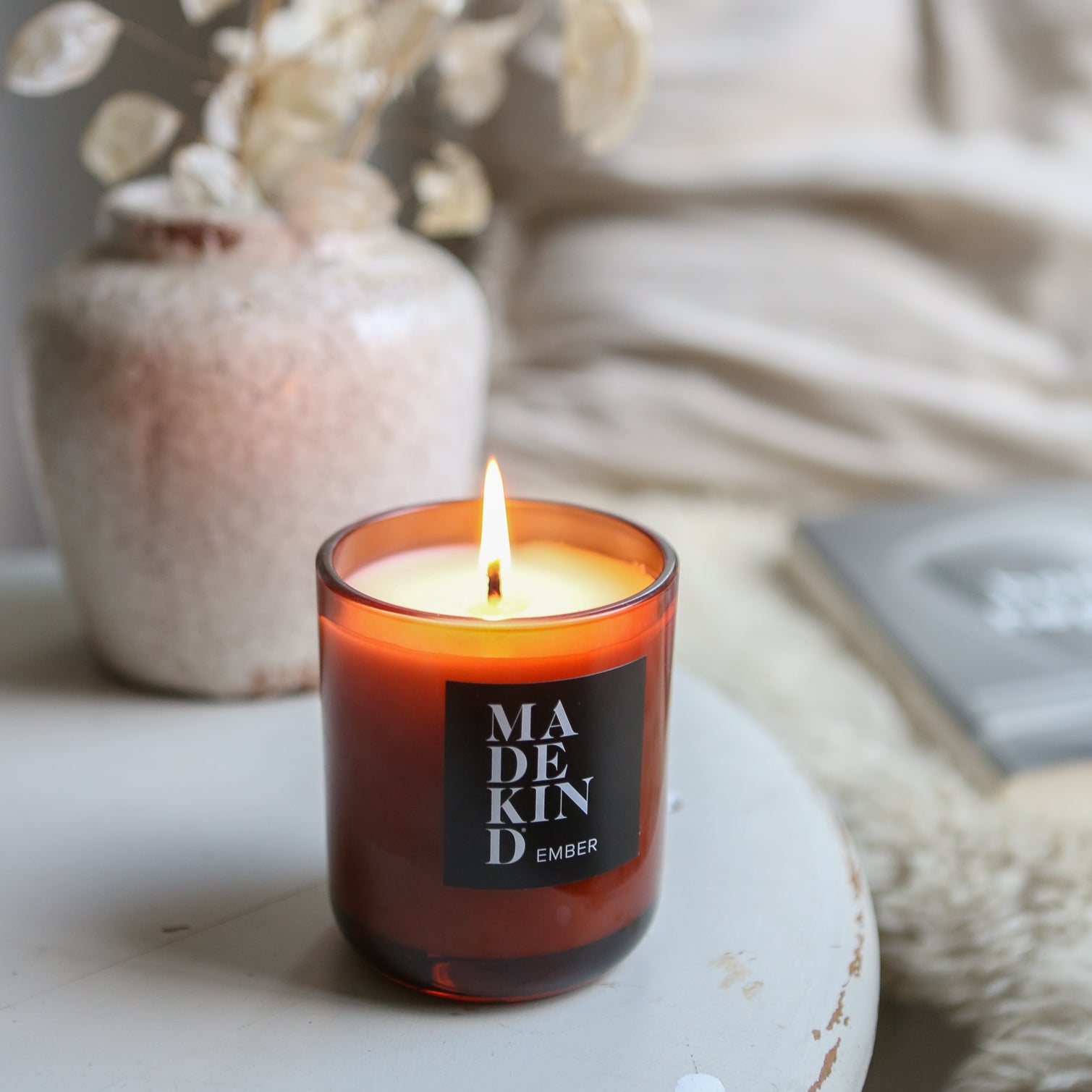 candle in amber jar on side table in cosy corner of home