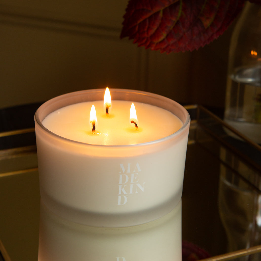 Three-wick sleep well candle in a white glass container with 'MadeKind' branding on the side. 
