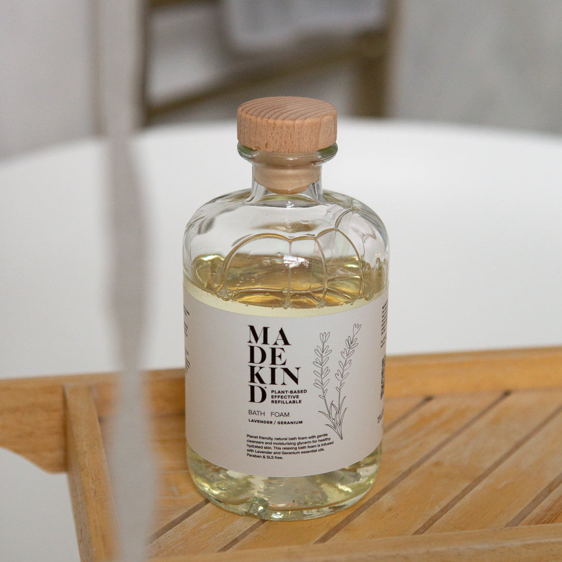 Bottle of Madekind Bubble bath on a wooden surface with a blurred background in a bathroom
