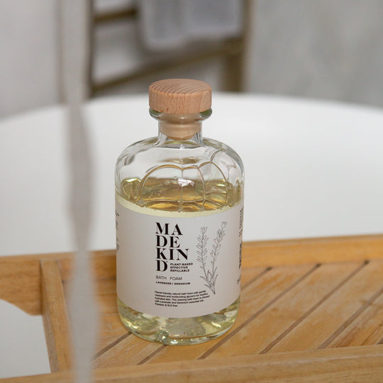 Bottle of Madekind Bath Foam on a wooden surface with a blurred background in a bathroom