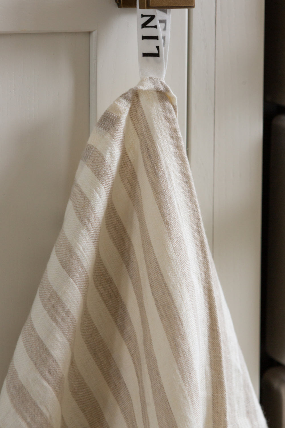 Photo of a hanging white and beige striped woven linen tea towel