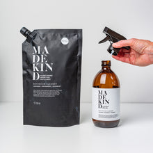 Load image into Gallery viewer, photo of 1 litre natural bathroom cleaner refill pouch with a MadeKind 500ml amber glass bottle with a hand holding the trigger spray.
