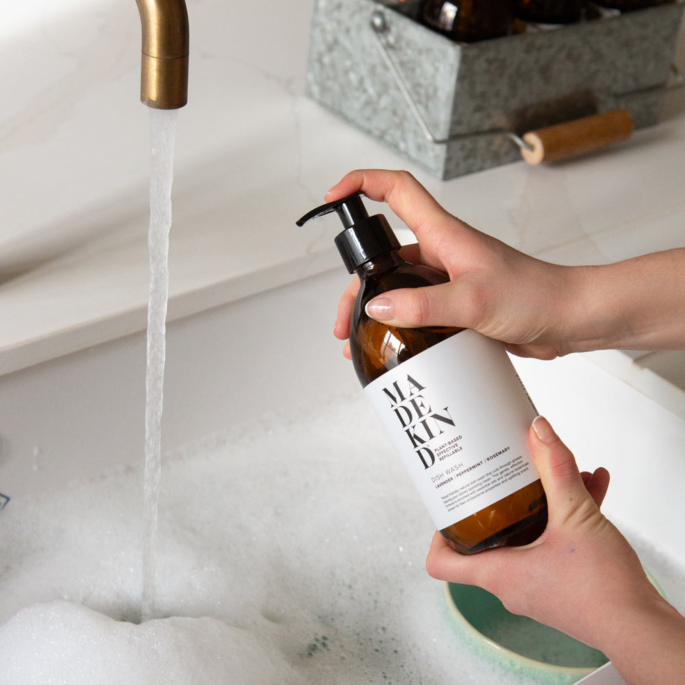 Photo of a person holding a MadeKind Dish Wash bottle over a sink