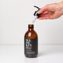 Load image into Gallery viewer, Photo of empty 300ml amber glass bottle with a hand holding the pump for lavender and geranium hand wash or hand lotion
