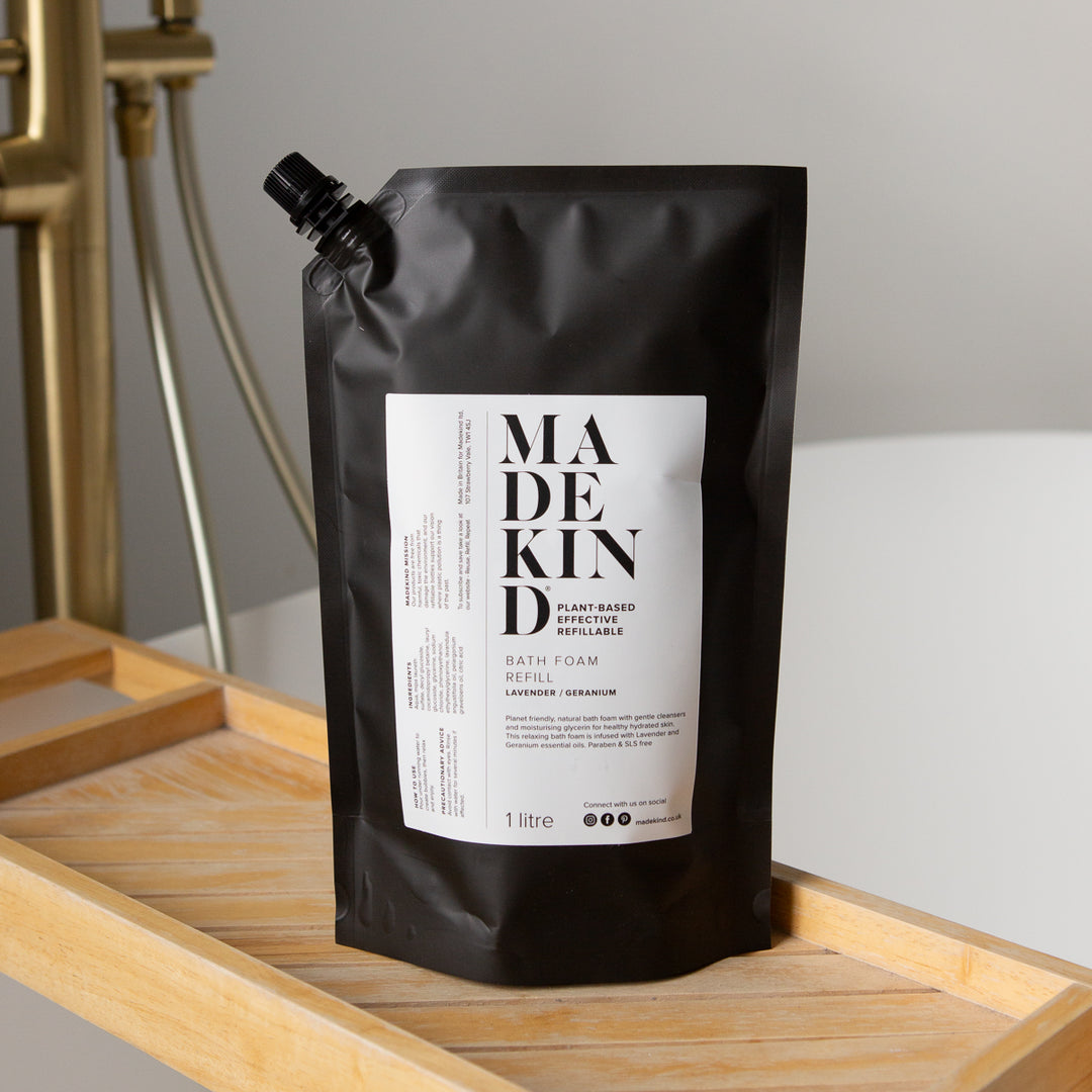 Photo of MadeKind Bath Foam 1 Litre Refill pouch on a wooden bath tidy with brass taps in the background 