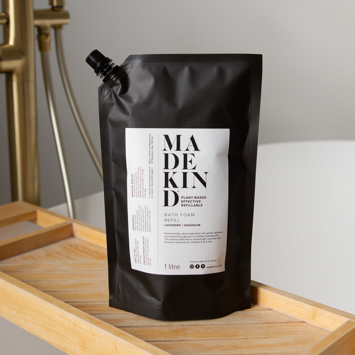 Photo of MadeKind Bath Foam 1 Litre Refill pouch on a wooden bath tidy with brass taps in the background 