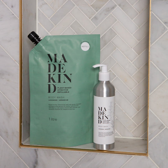 MadeKind Body Wash 1 Litre refill next to a refillable body wash aluminium bottle on a shower shelf
