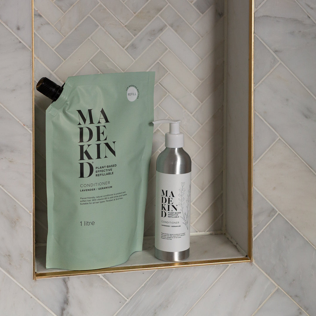 Made Kind conditioner refill pouch and matching pump bottle displayed on a marble shelf in a bathroom setting.