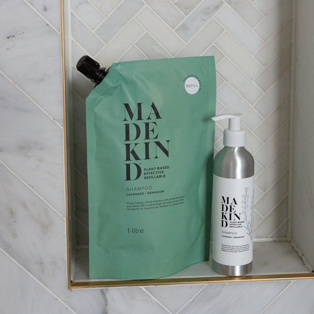 MadeKind Natural Shampoo Refill Pouch and refillable aluminium bottle on a shower shelf.