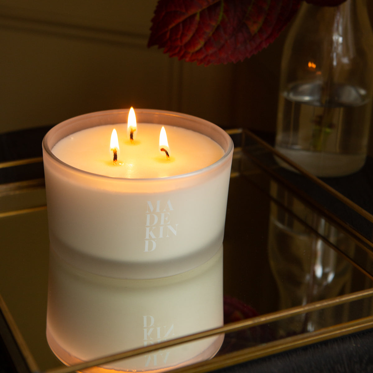 Photo of MadeKind Awaken soy wax aromatherapy candle in glass container.Lit candle on a mirrored glass tray.