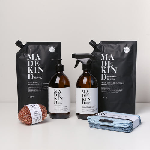 Photo of the MadeKind Kitchen Cleaning Kit; Multi Surface Cleaner and Dish Wash refills with 2 empty amber glass bottles, copper scourers and blue dishcloths