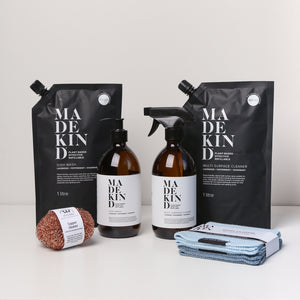 Photo of the MadeKind Kitchen Cleaning Kit; Multi Surface Cleaner and Dish Wash refills with 2 empty amber glass bottles, copper scourers and blue dishcloths