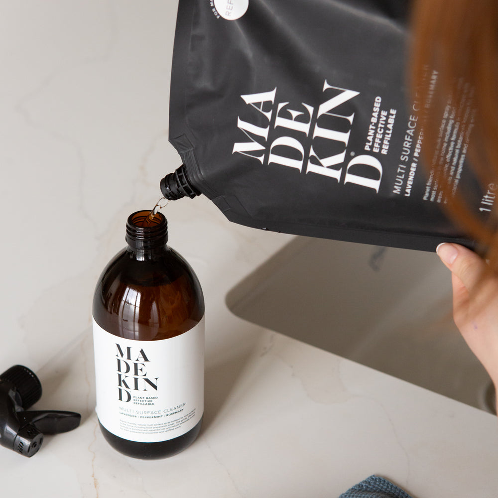 Photo of a MadeKind 1 Litre Multi Surface Cleaner refill pouch being poured into an empty amber glass bottle