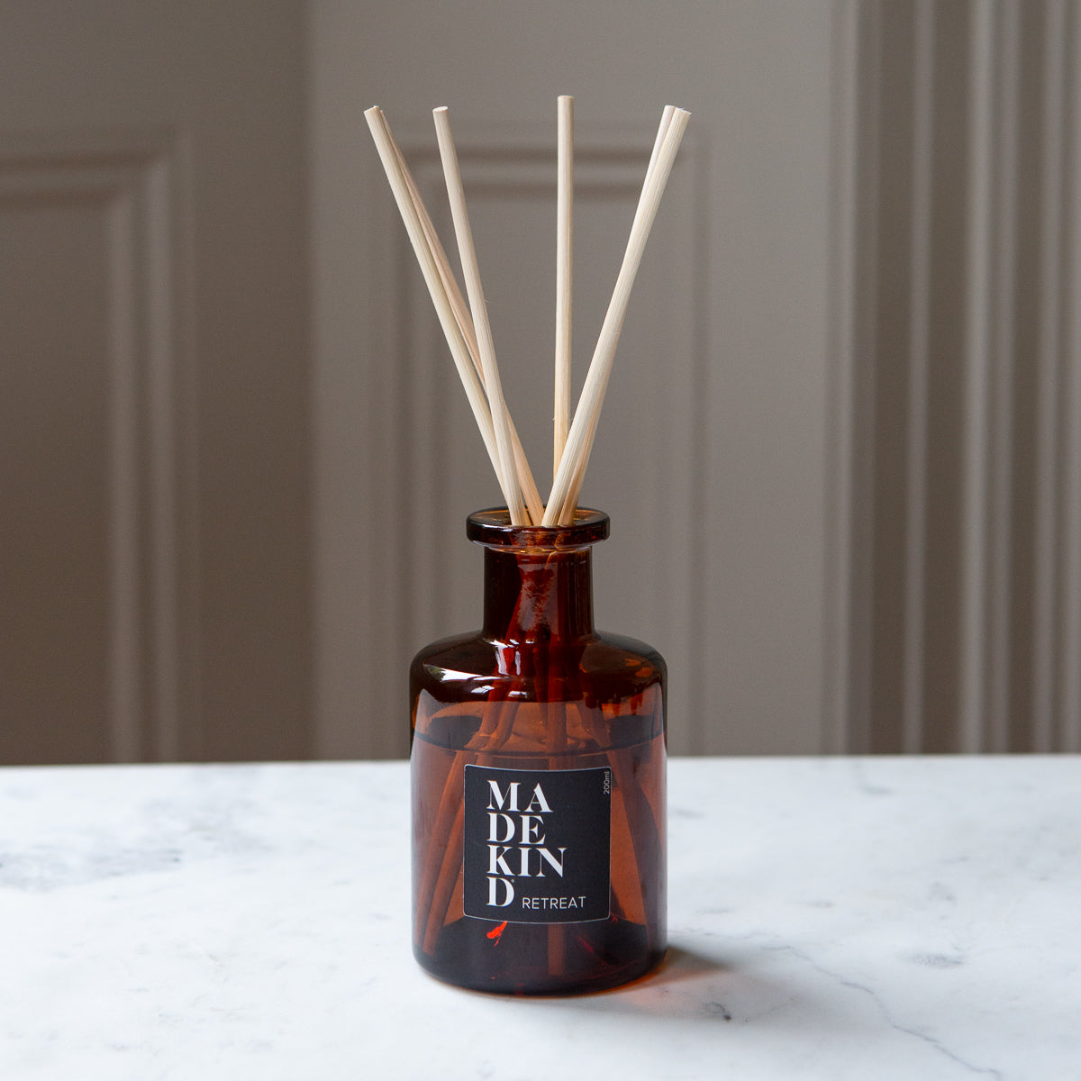 Amber glass apothecary reed diffuser bottle with natural reeds on a marble table