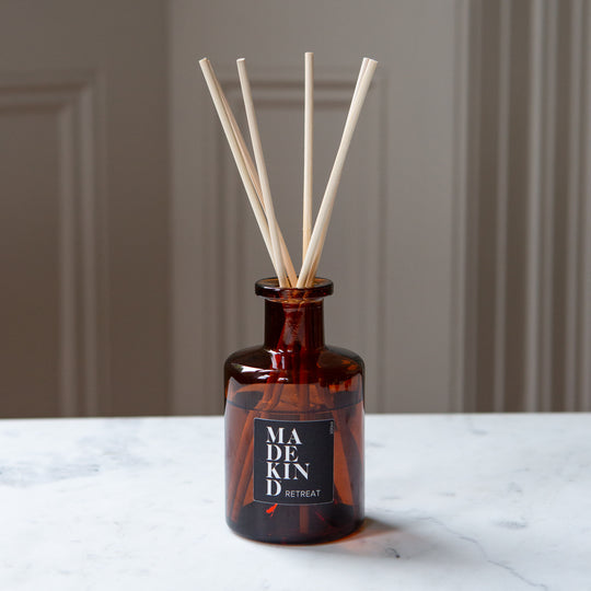 Amber glass apothecary reed diffuser bottle with natural reeds on a marble table