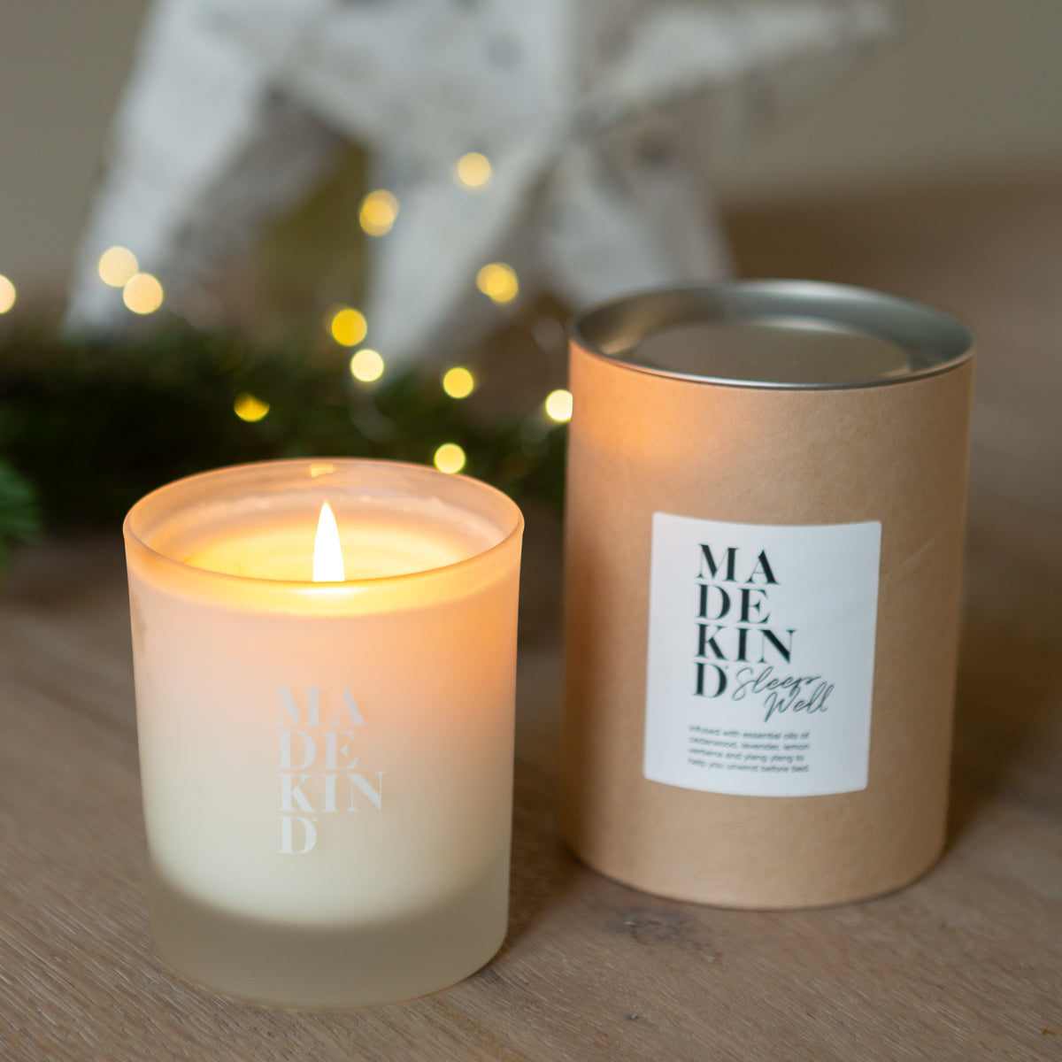 Candle and its packaging with 'MADEKIND' branding on a wooden surface.