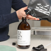 Load image into Gallery viewer, Photo of someone pouring a MadeKind multi surface cleaning refill pouch into a forever bottle
