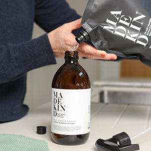 Photo of someone pouring a MadeKind multi surface cleaning refill pouch into a forever bottle