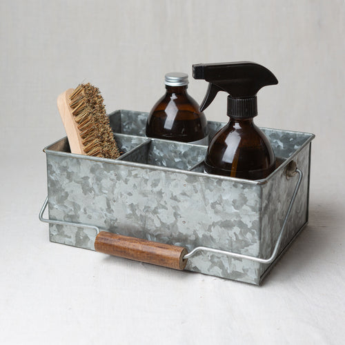 Photo of a brush and two bottles, one with a cap and one with a nozzle, sitting in a cleaning caddy