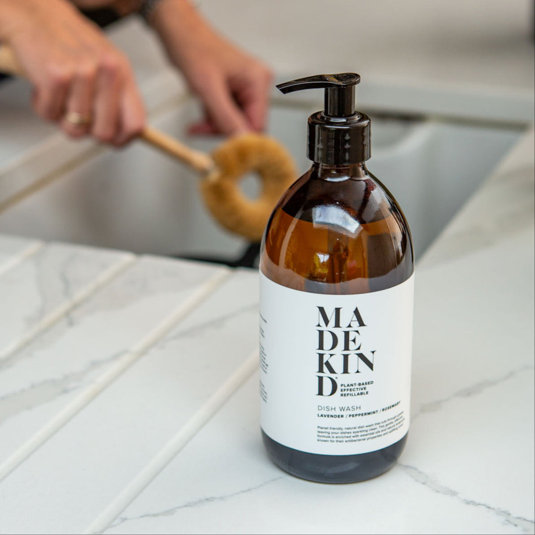 Photo of a MadeKind Natural, eco friendly dish wash in 500ml amber glass bottle next to a kichen sink