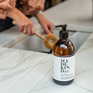 Photo of a MadeKind Natural, eco friendly dish wash in 500ml amber glass bottle next to a kichen sink