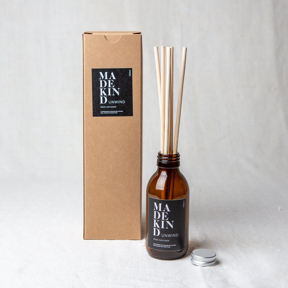 Photo of MadeKind Awaken aromatherapy reed diffuser in glass amber bottle. Pure essential oil blend includes Rose, Jasmine and Ylang Ylang. Reeds come included and presented in a Kraft gift box.